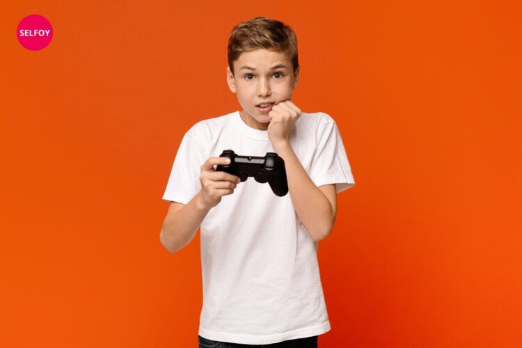 Boy has remote control of video game in hand and looks fearing and depicts low self esteem