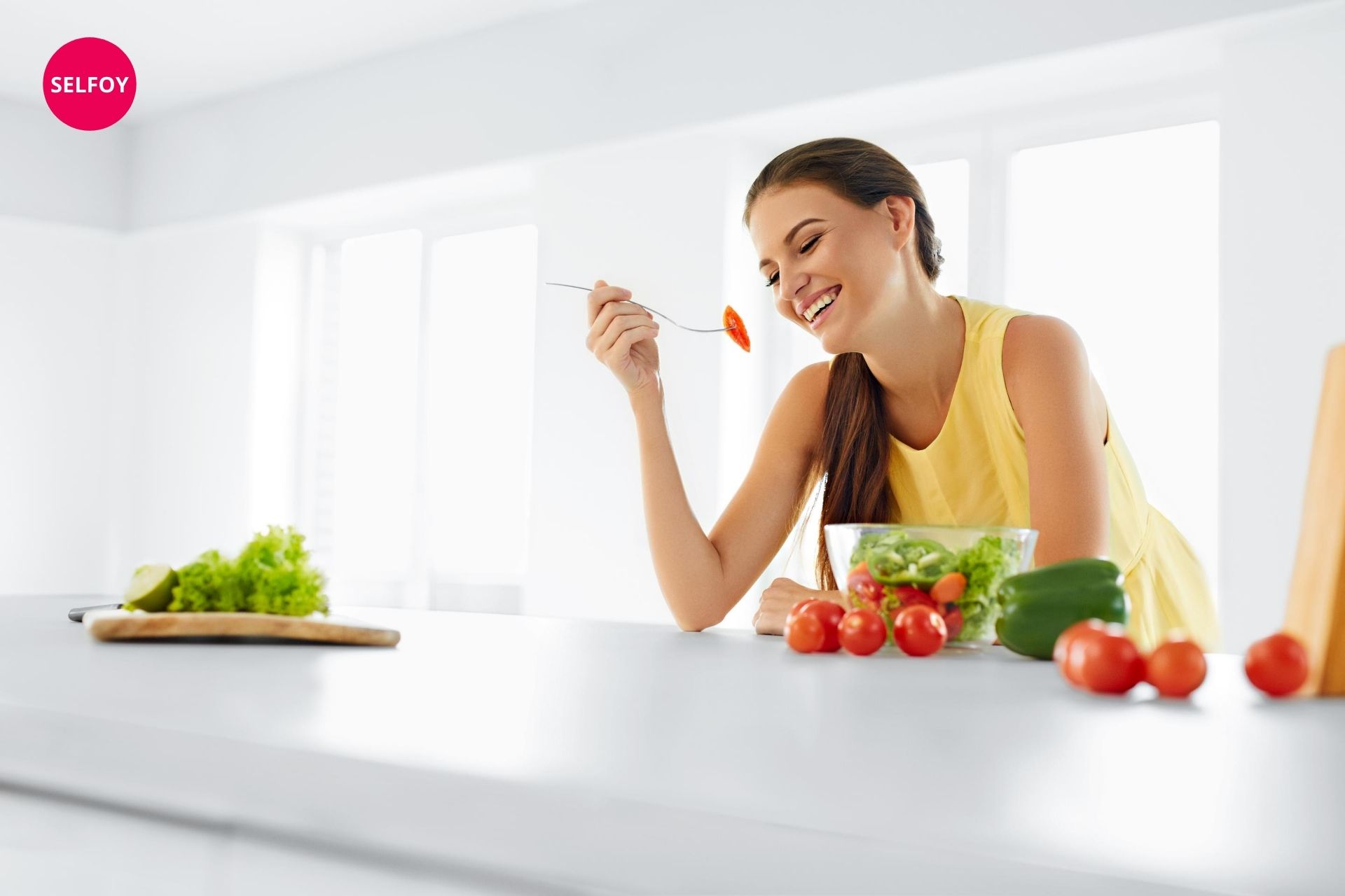 Woman wearing yellow top having spoon and eating salad