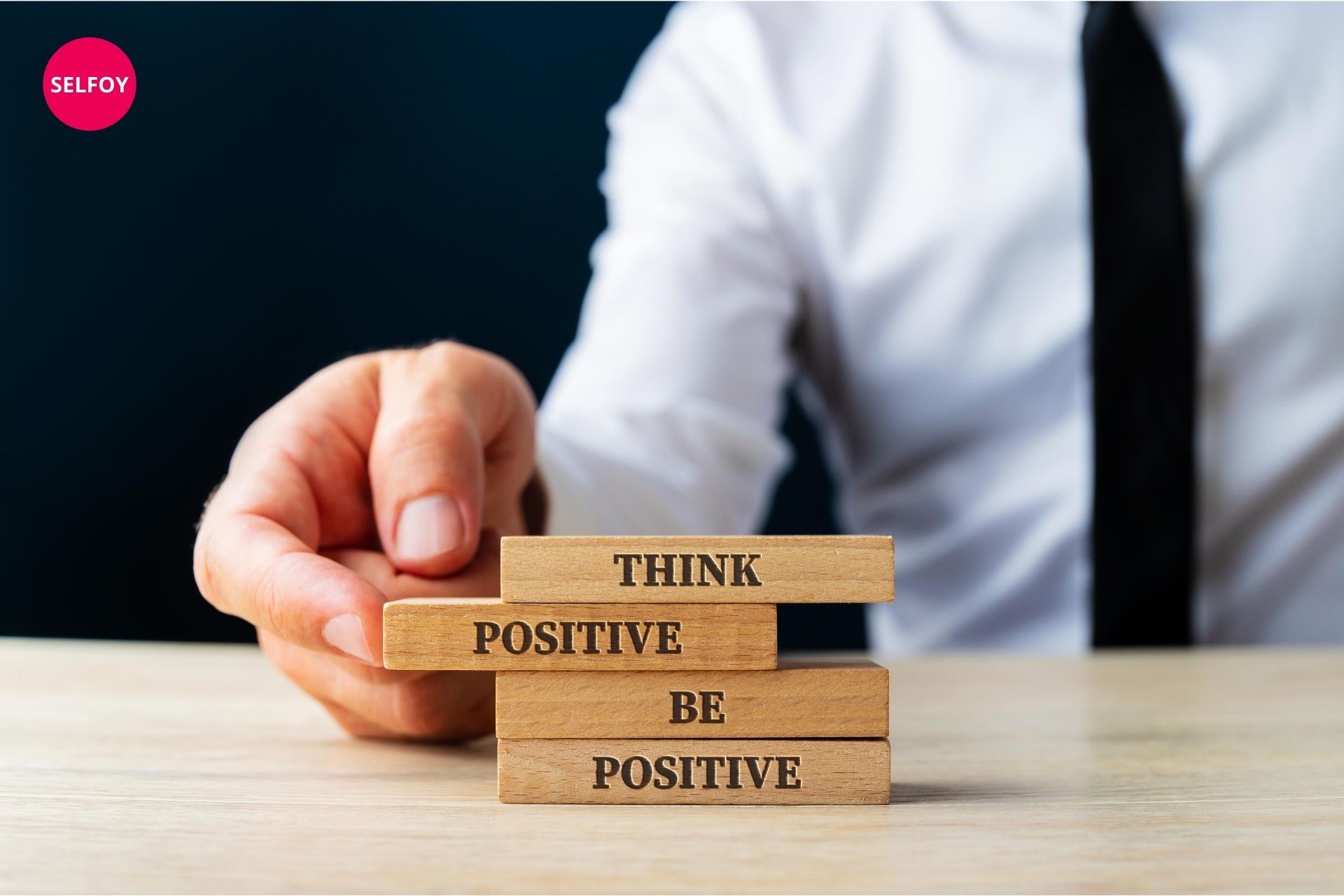 Man's hand holding wooden art written think positive be positive