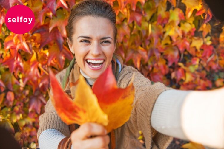 One woman is laughing and holding orange colored leafs 